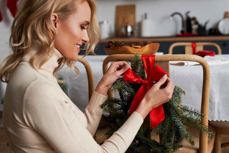 Woman ties bow around wreath on chair