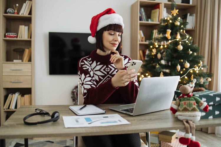 Business woman wearing Santa hat works at desk